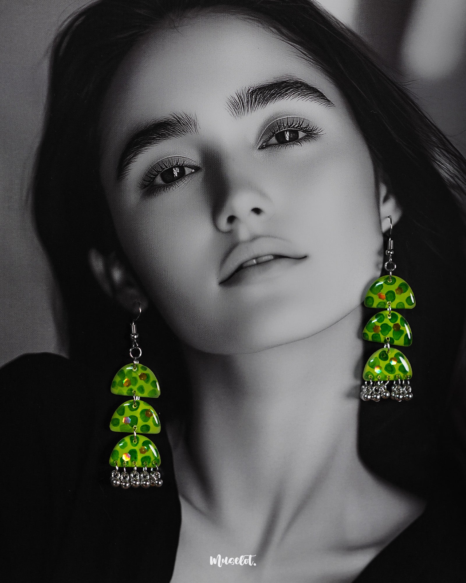 A woman wears the Parvaaz handmade green drop earrings, flaunting their tiered semicircle silhouette and dotted leafy design that highlights nature’s vibrancy and showcases a playful, artisanal flair — Muselot.