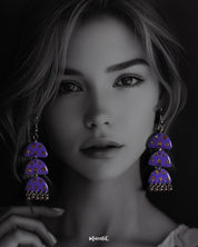 A woman wearing the Parvaaz handmade purple drop earrings, with delicate motifs and an elegant curved shape, highlighting the intricate craftsmanship and showcasing how effortlessly they add charm to a contemporary look — Muselot.