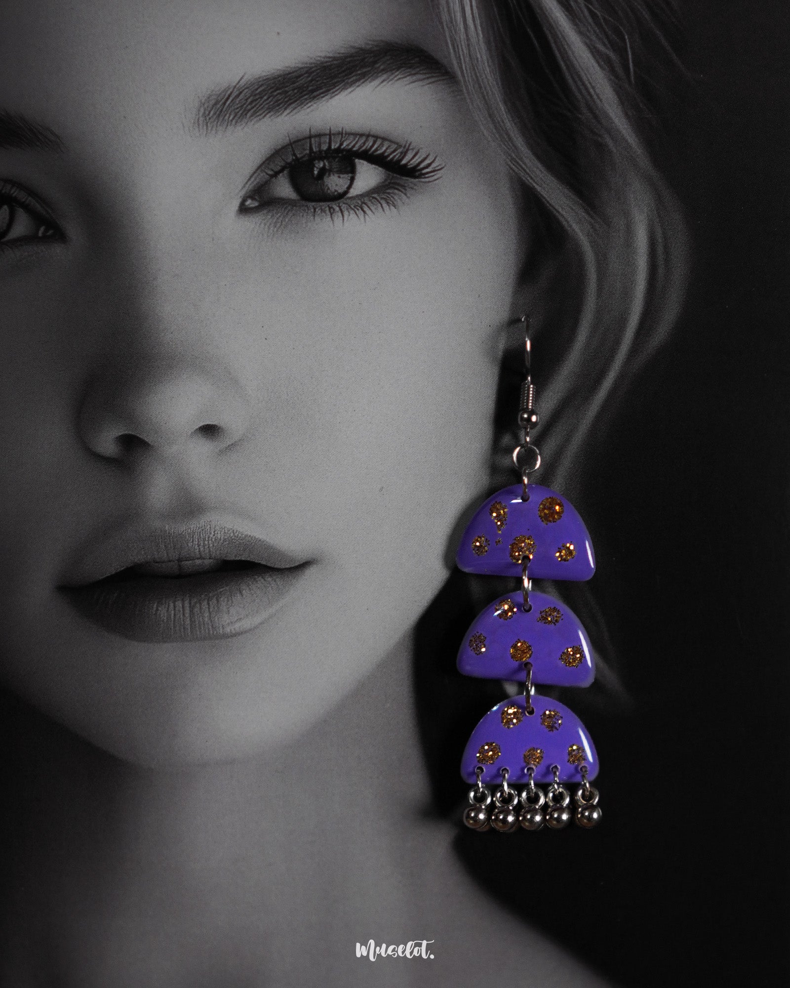 Close-up view of a woman wearing the Parvaaz handmade purple drop earrings, highlighting the fine detailing of the floral design and showcasing the artisanal charm and vibrant elegance they bring to the overall look — Muselot
