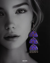 Close-up view of a woman wearing the Parvaaz handmade purple drop earrings, highlighting the fine detailing of the floral design and showcasing the artisanal charm and vibrant elegance they bring to the overall look — Muselot
