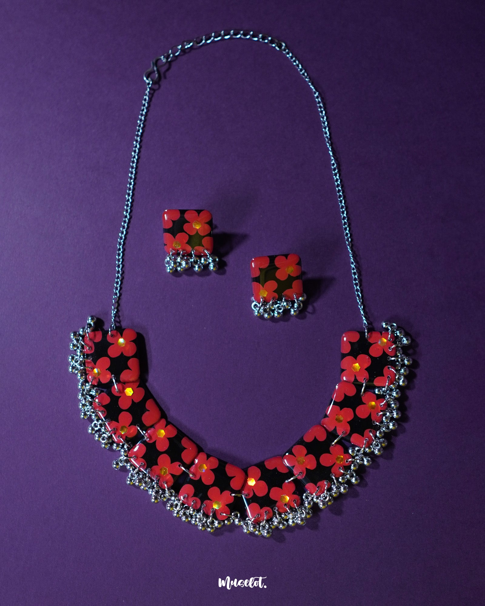 The Raktphool floral jewelry set features intricate floral motifs, beautifully crafted to enhance your style, set against a rich purple background — Muselot.