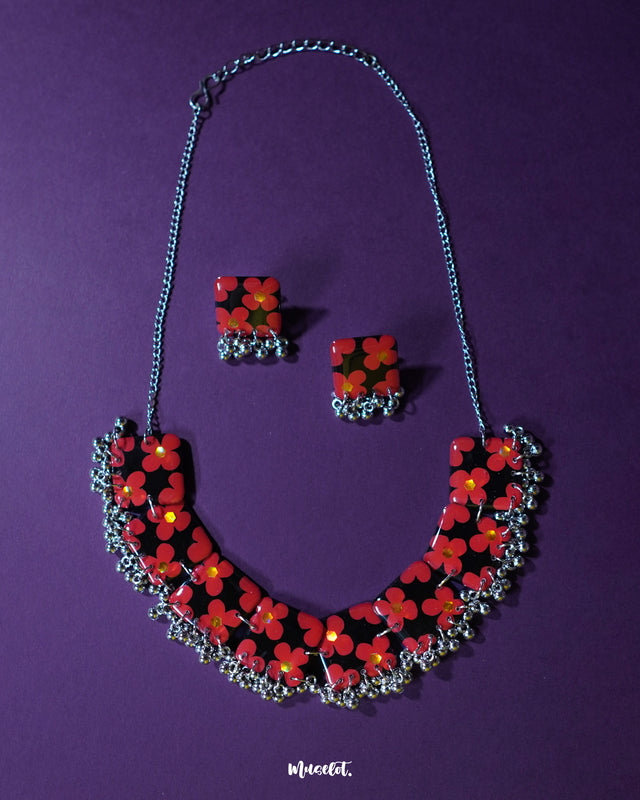 The Raktphool floral jewelry set features intricate floral motifs, beautifully crafted to enhance your style, set against a rich purple background — Muselot.