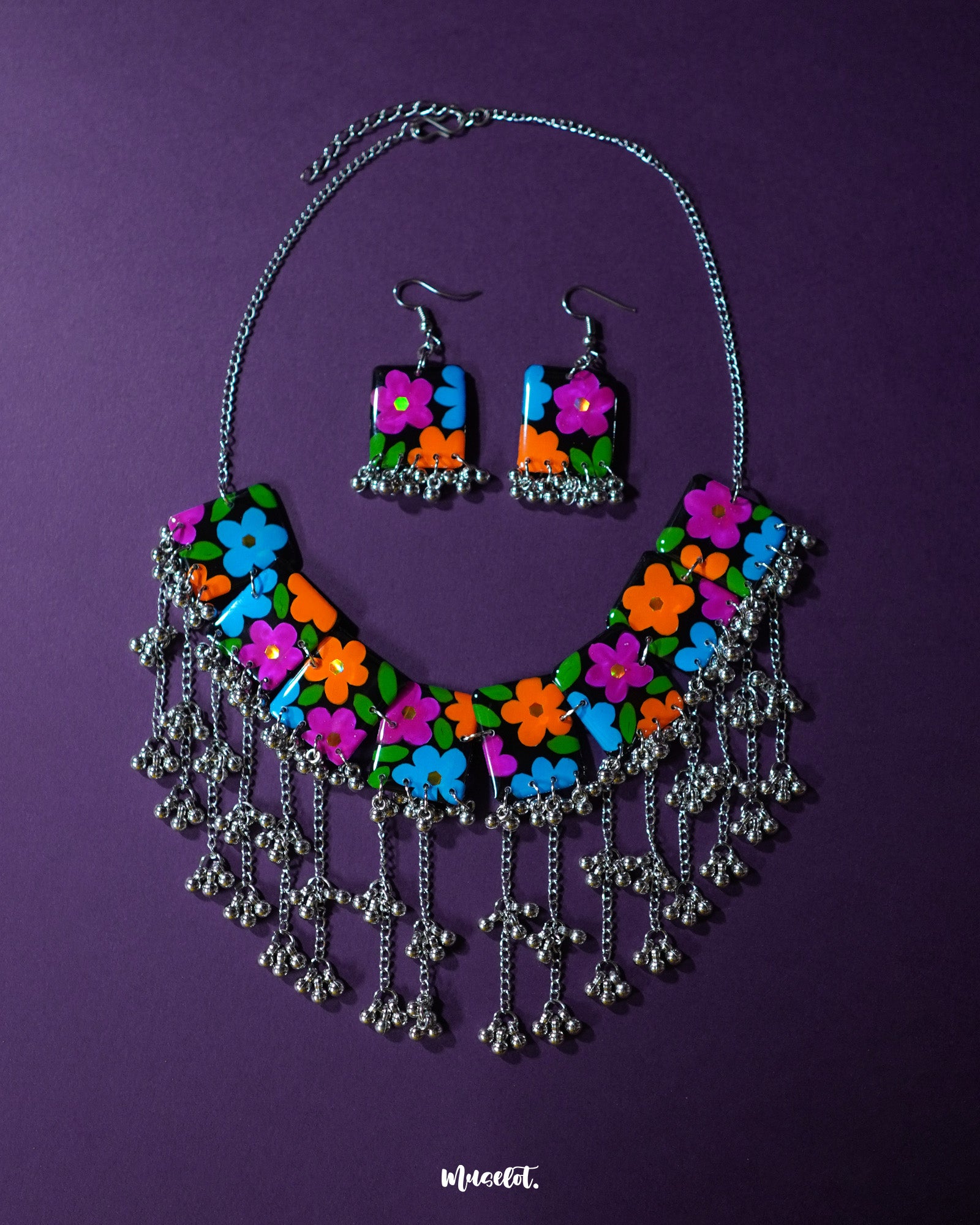 A vibrant shot of the Rangbaagh black floral necklace set placed against a rich purple background, showcasing its handcrafted floral detailing and bold black accents that create a striking contrast — Muselot