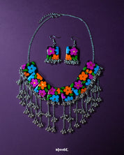 A vibrant shot of the Rangbaagh black floral necklace set placed against a rich purple background, showcasing its handcrafted floral detailing and bold black accents that create a striking contrast — Muselot