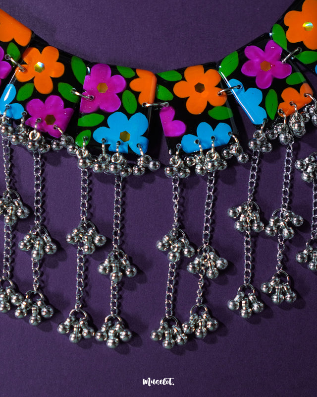The Rangbaagh black floral necklace set displayed against a rich purple background, highlighting the handcrafted floral elements, dark beadwork, and elegant symmetry of the traditional design — Muselot