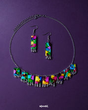 A vibrant handmade necklace set featuring colorful beads, playful ghungroos, and detailed threadwork is artfully arranged on a flat surface. The bold and festive tones of the jewelry evoke traditional Indian charm, making it a statement piece perfect for ethnic or boho-inspired looks – Muselot.