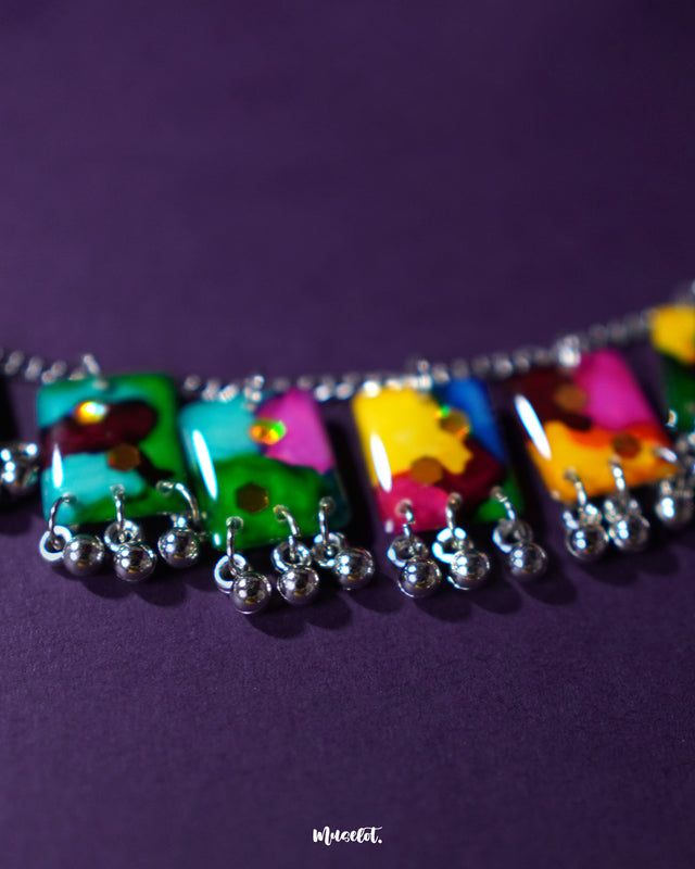 Zoomed-in view of the Rangbaari colorful jewelry set, showcasing the detailed multicolor abstract patterns on rectangular charms with silver bead accents, capturing the vibrant artistry and fine craftsmanship – Muselot.