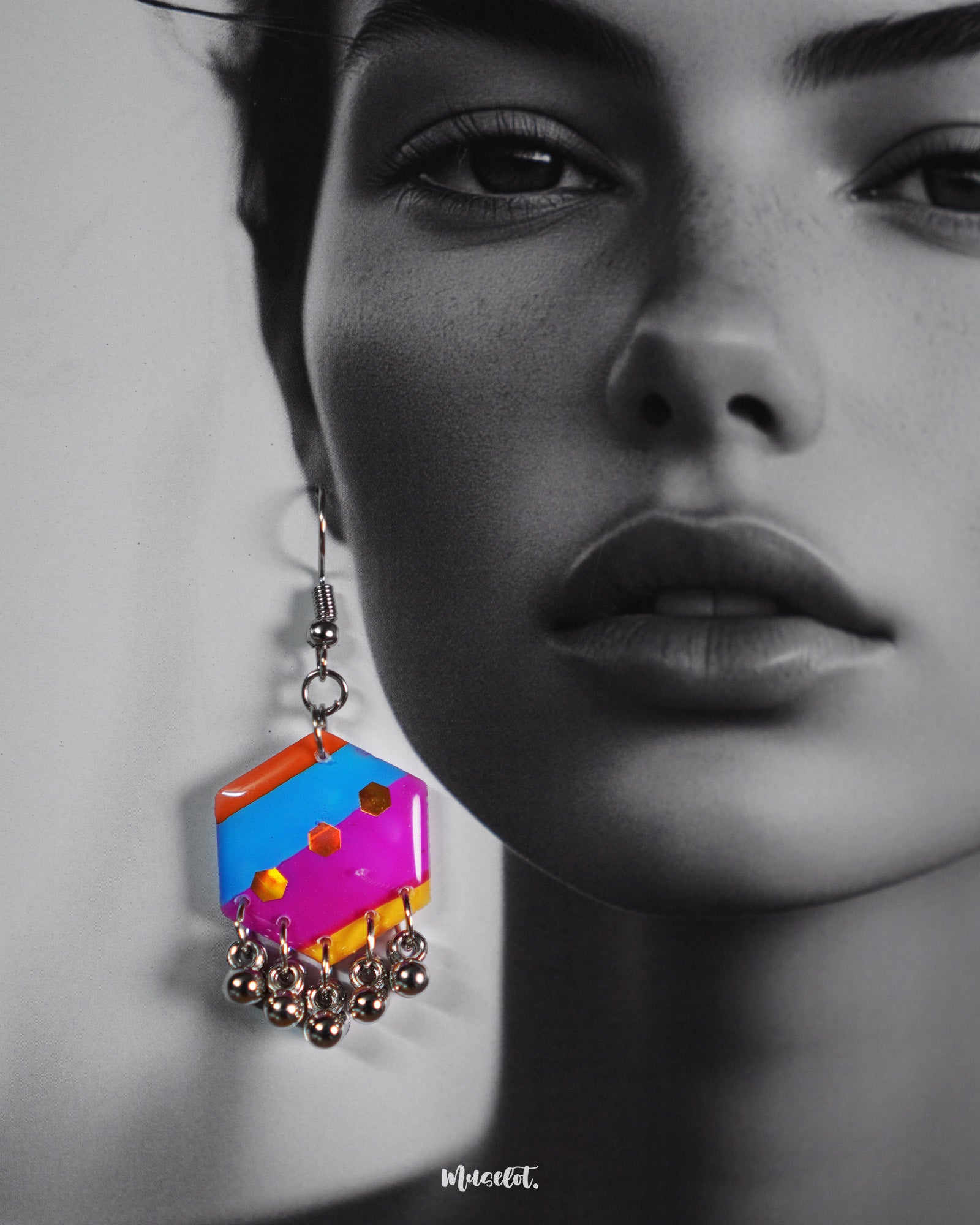 Close-up of a model wearing the Rangbahaar hook earrings, highlighting the vibrant geometric pattern in orange, yellow, pink, and blue, accented with reflective sequins and silver-toned dangling beads that enhance the festive flair — Muselot.
