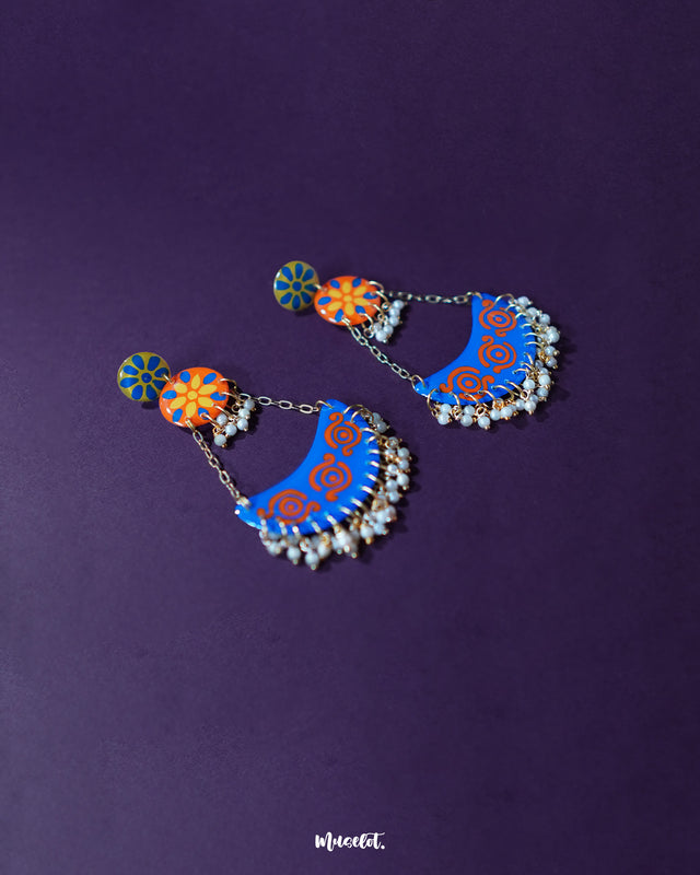 The Ranglahar blue chandbaali earrings displayed against a soft background, featuring intricate enamel detailing in blue and orange with delicate pearl danglings—crafted to add regal charm to festive looks — Muselot.