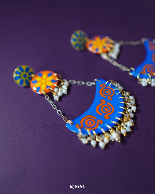 A closer look at the Ranglahar blue chandbaali earrings reveals the intricate enamel work and radiant blue crescent base, highlighted with vibrant orange detailing and dainty pearls. These handcrafted beauties strike the perfect balance between ethnic charm and contemporary color play — Muselot.