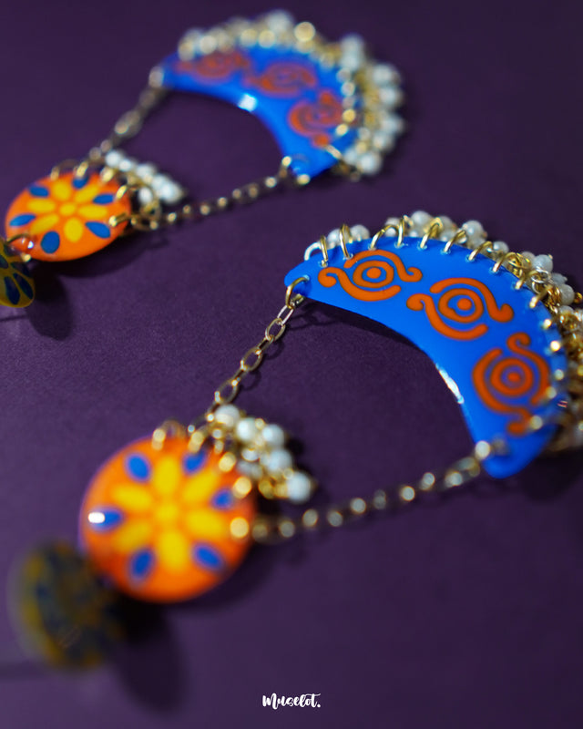 A closer view of the Ranglahar blue chandbaali earrings, showcasing their ornate crescent shape, vibrant enamel work, and pearl accents that blend traditional artistry with modern grace — Muselot.