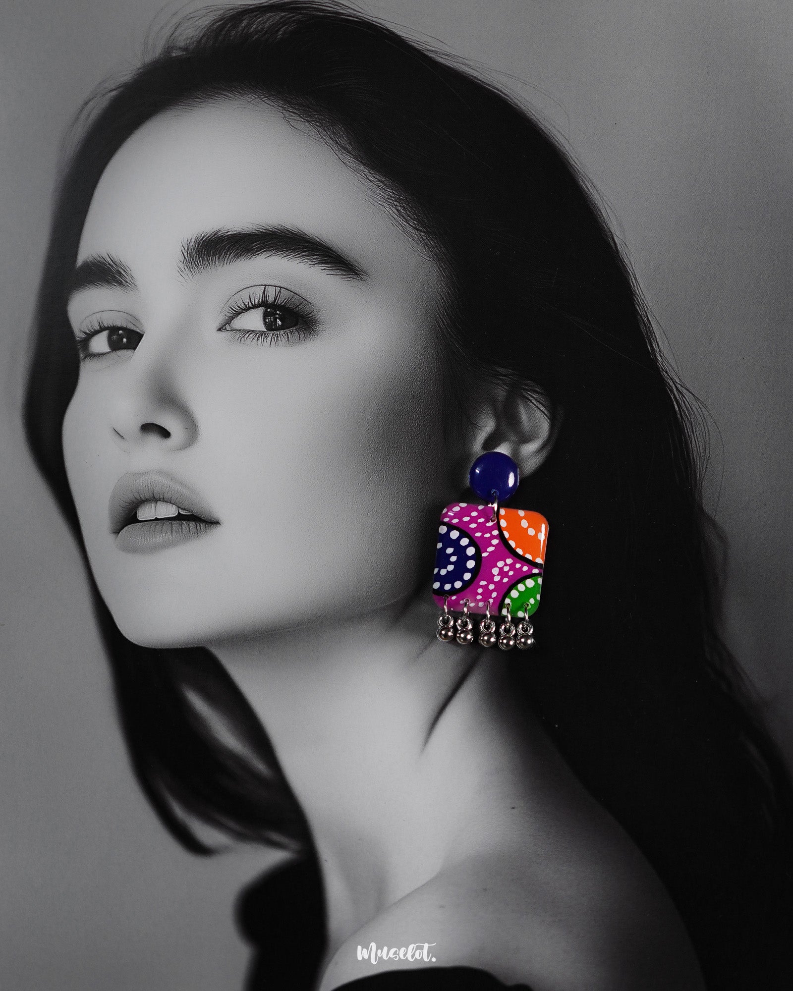 a model wearing Rangras folk art stud earrings, highlighting the vibrant colors and detailed patterns that bring a fusion of cultural heritage and contemporary elegance to the overall style — Muselot.