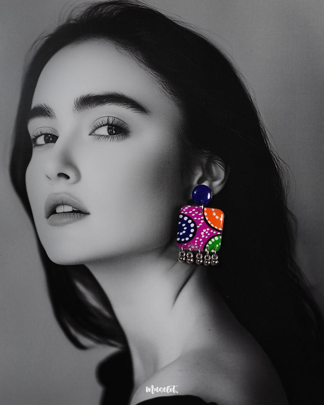 a model wearing Rangras folk art stud earrings, highlighting the vibrant colors and detailed patterns that bring a fusion of cultural heritage and contemporary elegance to the overall style — Muselot.