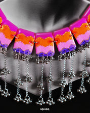 A woman wears the Rangrezan handmade colorful necklace, its vivid chevron beads in pink, orange, purple, and blue gracefully lining her neckline, while silver-toned accents add a traditional charm to the bold, bohemian vibe — Muselot.
