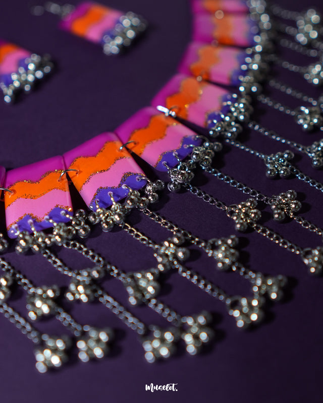 The Rangrezan handmade colorful necklace set rests elegantly against a rich purple background, highlighting its intricate beadwork and vibrant hues that capture the spirit of folk artistry — Muselot.