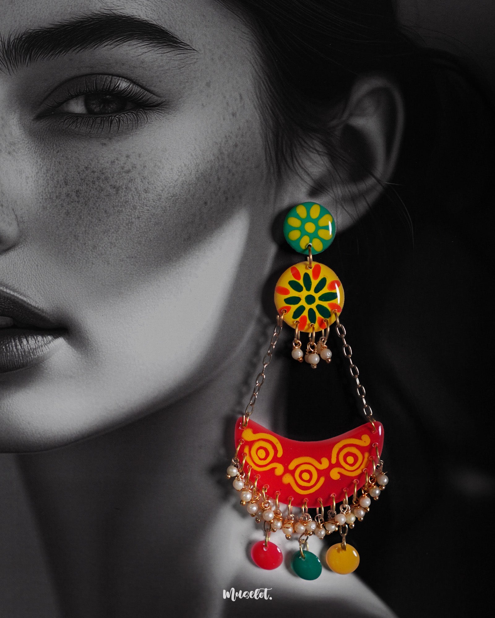 A close-up of a woman wearing the Rangsiya chandbali earrings, showcasing their vivid red, yellow, and green enamel work, pearl bead detailing, and colorful dangling discs — an eye-catching blend of tradition and playfulness that lights up the look — Muselot.