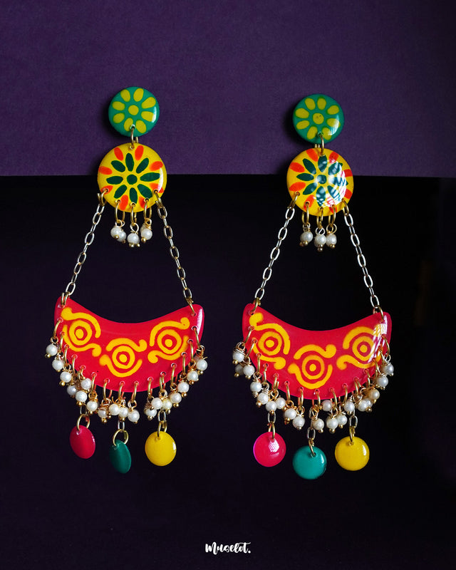 Rangsiya chandbali earrings bursting with festive flair — featuring a vibrant mix of red, yellow, and green enamel, delicate pearl-like beads, and playful danglers, all brought together with golden chains for a statement look against the purple backdrop — Muselot.