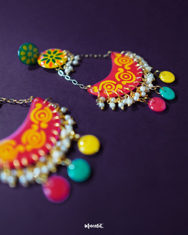 A close look at the Rangsiya colorful chandbali earrings reveals their fine craftsmanship — the hand-painted enamel work in bright red and yellow tones is beautifully complemented by the dainty pearl clusters and antique gold finish — Muselot.