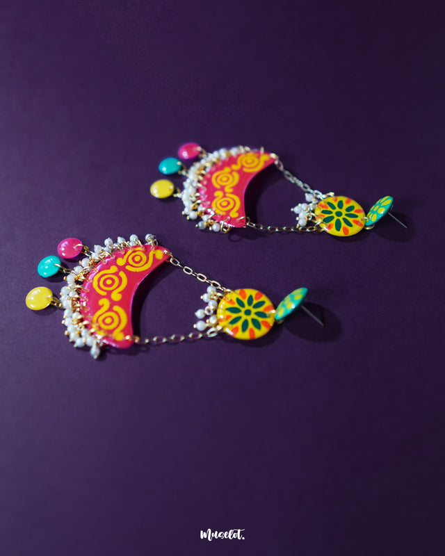 The Rangsiya colorful chandbali earrings rest gracefully, showcasing a vibrant palette of red and yellow with intricate detailing, finished with pearl accents that lend a festive charm — Muselot.