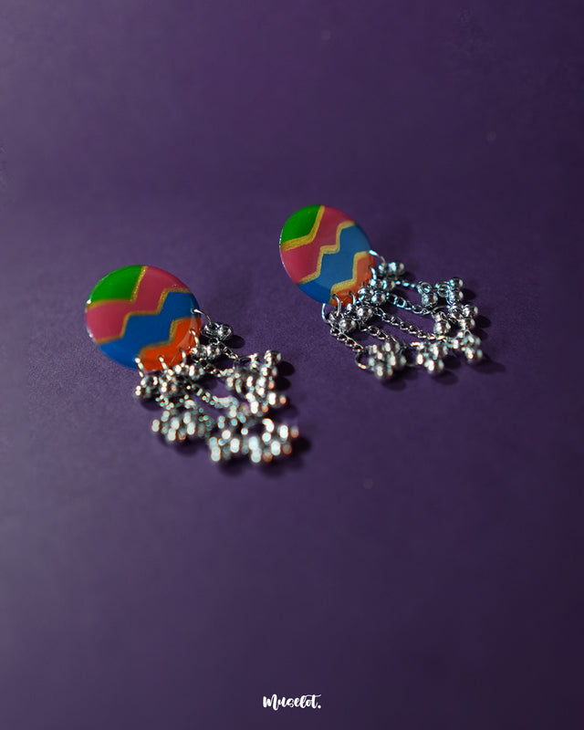 Rangtarang colorful long chain earrings shown resting against a rustic surface, highlighting the intricate hand-painted detailing and multicolor accents that add depth and charm to these statement earrings – Muselot.