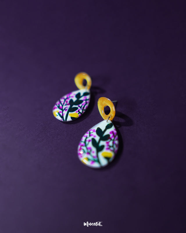 Close-up of Raushanbahaar floral drop earrings, capturing the teardrop shape adorned with pink and yellow hand-painted flowers and leafy accents, highlighting vibrant artistry and showcasing the intricacy of handmade design — Muselot.