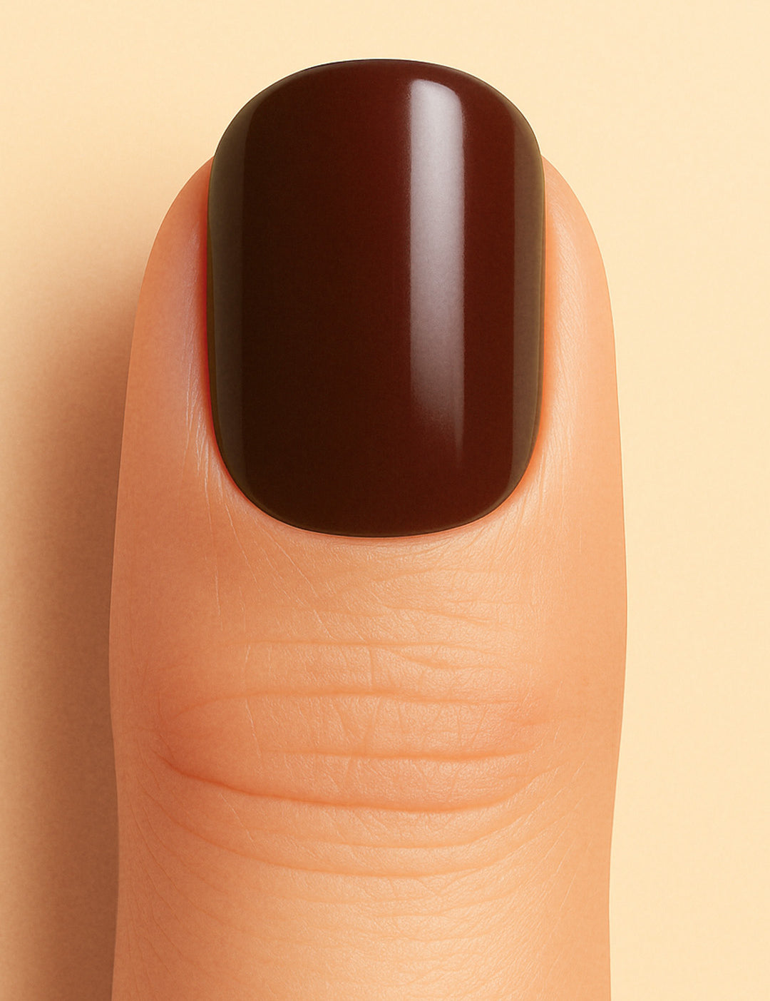 A close-up shot of a model finger wearing Rich Cocoa nail stickies, showcasing the deep chocolate-brown shade with a smooth glossy finish, highlighting the bold sophistication and elegance of minimal solid nail art – Muselot.
