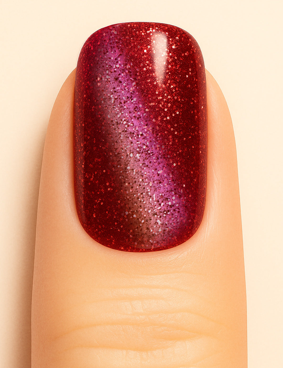 A close-up of a model’s finger wearing Romantic Ruby Cat Eye Nail Stickies, featuring a dazzling ruby-red base with a magnetic cat-eye shimmer effect that shifts into deep purple tones, enhanced with fine glitter sparkles for a bold and glamorous manicure – Muselot.