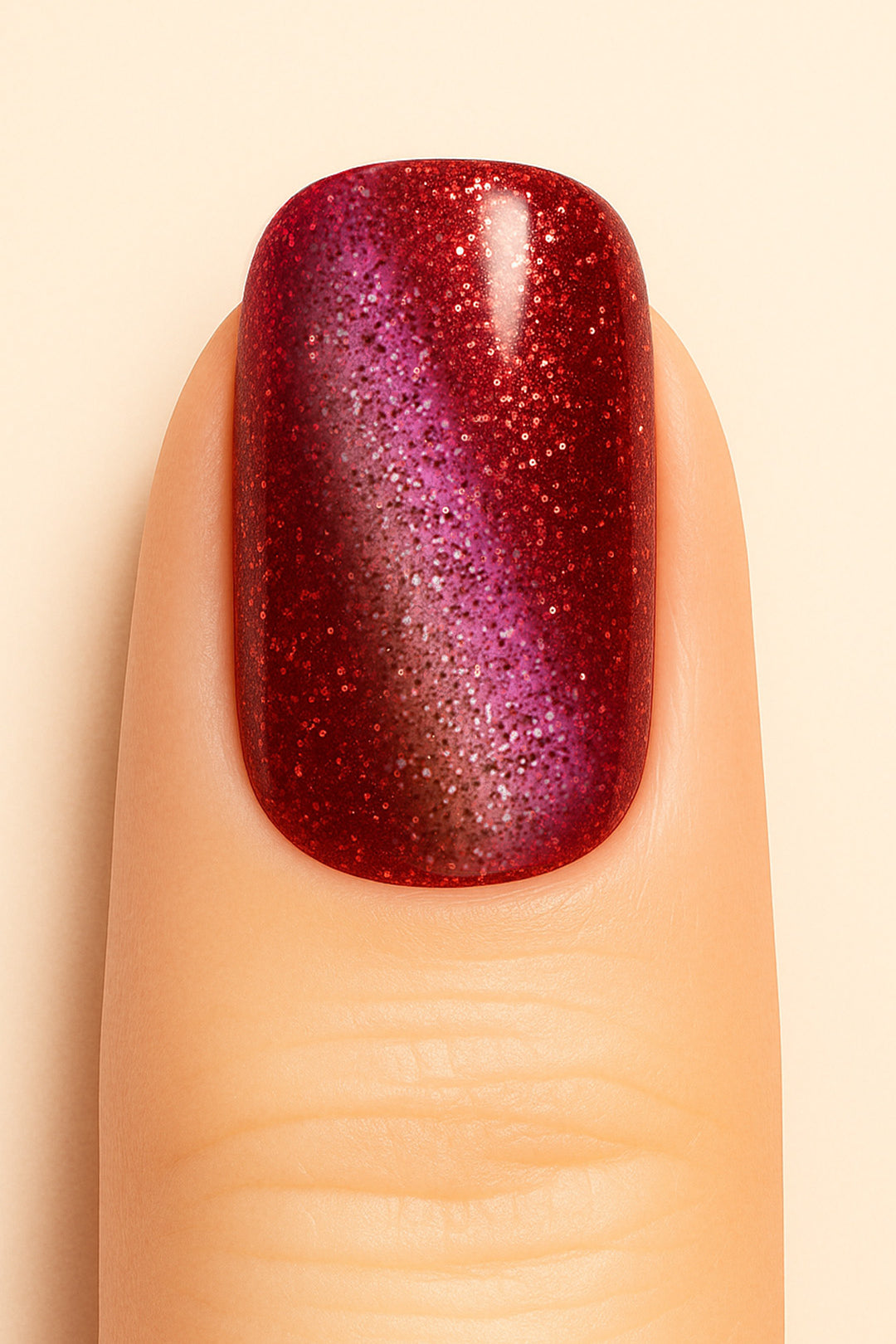 A close-up of a model’s finger wearing Romantic Ruby Cat Eye Nail Stickies, featuring a dazzling ruby-red base with a magnetic cat-eye shimmer effect that shifts into deep purple tones, enhanced with fine glitter sparkles for a bold and glamorous manicure – Muselot.