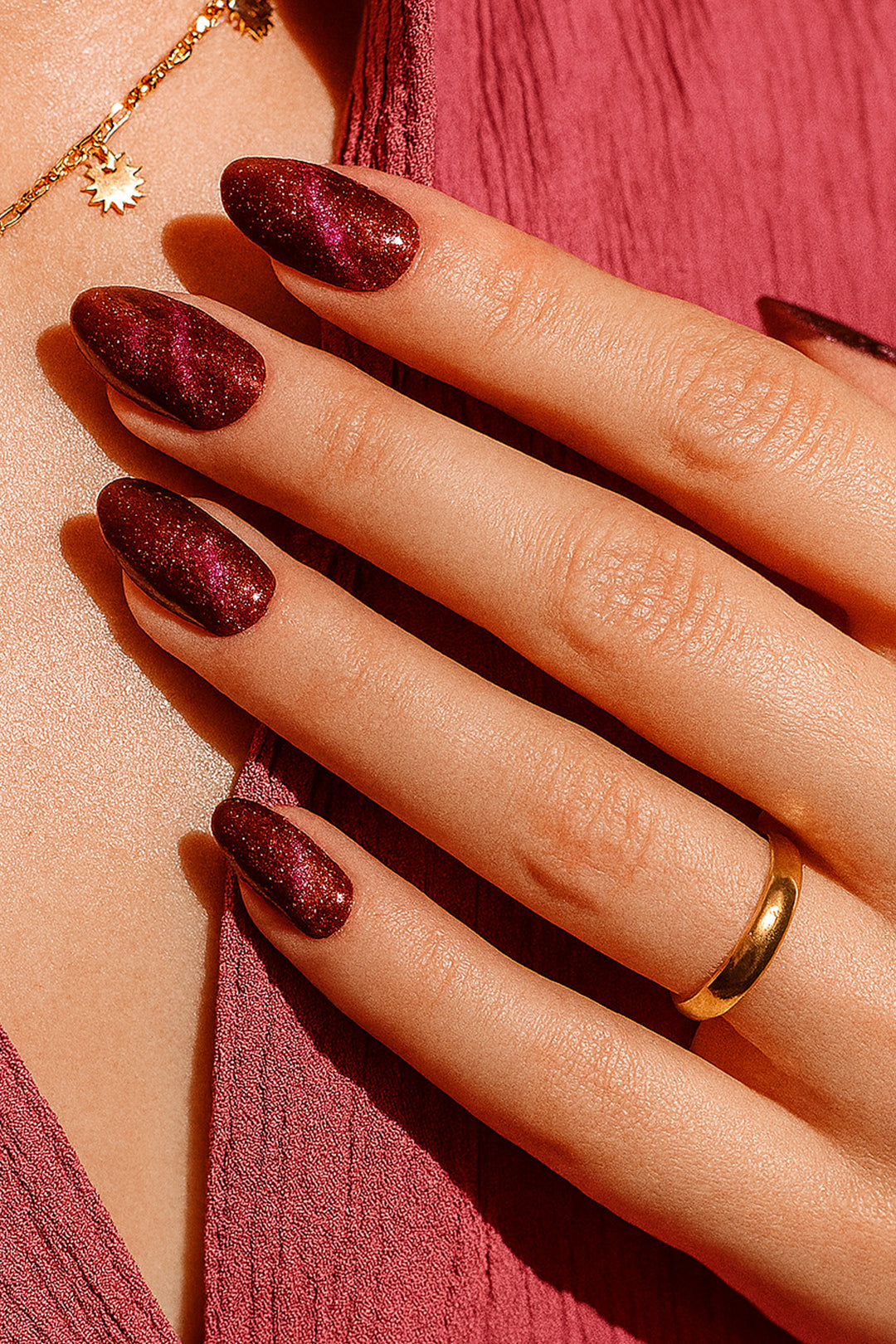 A model hand wearing Romantic Ruby Maroon Cat Eye Nail Art Stickers, showcasing a deep maroon-red base with a shimmering cat-eye effect that reflects light for a dazzling magnetic shine, adding a bold and glamorous finish – Muselot.