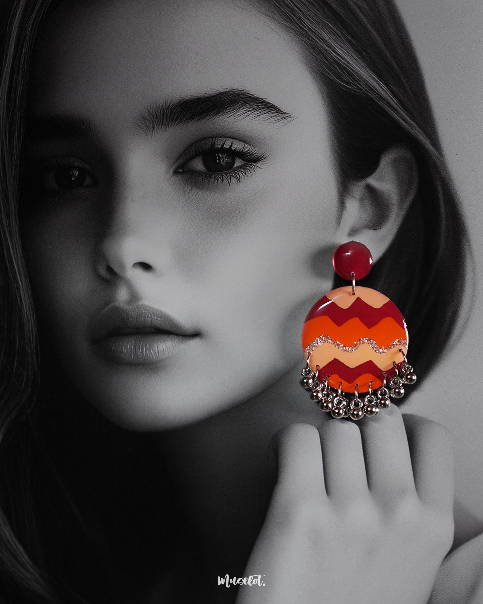 A close-up of the Sahar hook earrings worn by the model, showcasing the striking blend of maroon, orange, and mustard zigzag patterns, accented with shimmering silver ghungroos that dance with movement — Muselot.