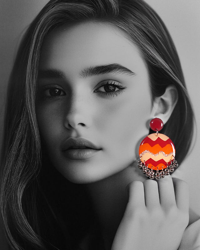 A model wearing the Sahar hook earrings, where the vivid maroon, orange, and mustard waves pop boldly against the dark backdrop, while the playful silver ghungroos add a rhythmic charm to the handcrafted design — Muselot.