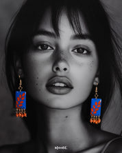 A model wears the Sandhyaraag boho drop earrings, highlighting the vivid blue base with bold orange petal motifs, showcasing their artsy design and vibrant charm — Muselot.