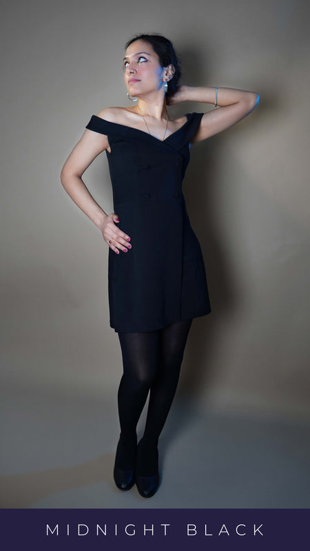 A woman wearing black breathable semi opaque tights for women, posing with her hand behind her back and other on her waist as she stands against a grey background, highlighting a sexy voguish look-Muselot