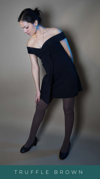 A woman wearing dark brown semi opaque tights, posing with her hand touching her thigh as she bend slightly forward while standing sideways, showcasing the durable smooth texture-Muselot