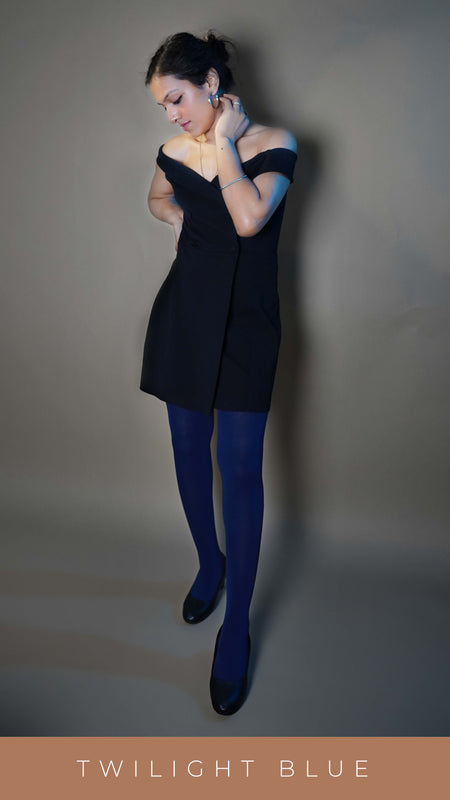 A model wearing cute plus size tights, posing with her hand on her neck and other on her waist as she stands slightly sideways looking down at her dress, showcasing the classy perfect fit-Muselot