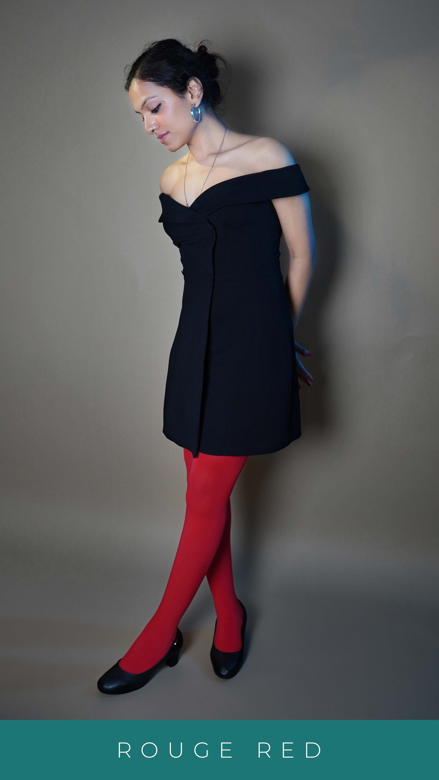 A woman wearing women's red colored stockings, posing with her hands tied at her back as she stands sideways against a grey background, looking down at her feet, showcasing the in demand comfortable look-Muselot