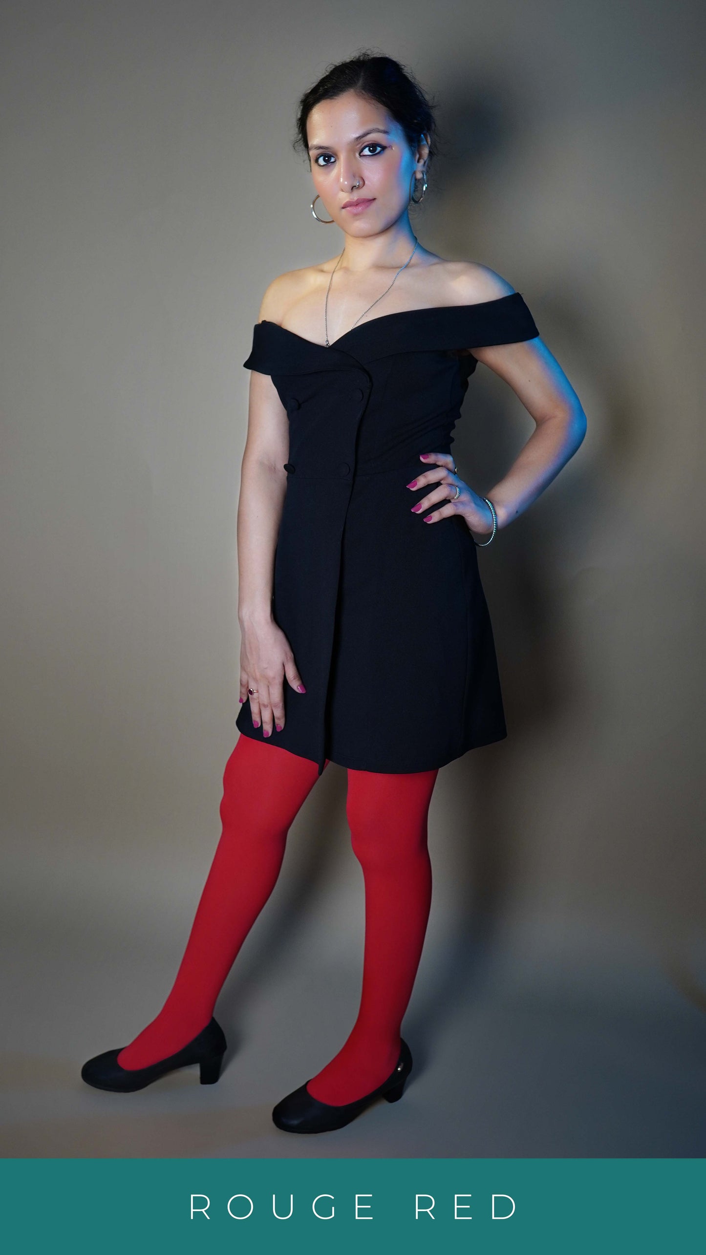 A woman wearing a girl's semi opaque red colored pantyhose, posing with her hand on her waist and other at her front looking at the camera, showcasing the durable smooth texture-Muselot