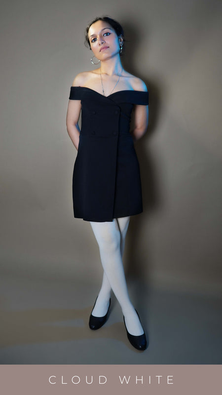 A classy model wearing semi opaque tear proof white stockings, posing with her hands tied at her back as she looks at the camera with her head held high and slightly bent sideways, highlighting a modern elegant look-Muselot