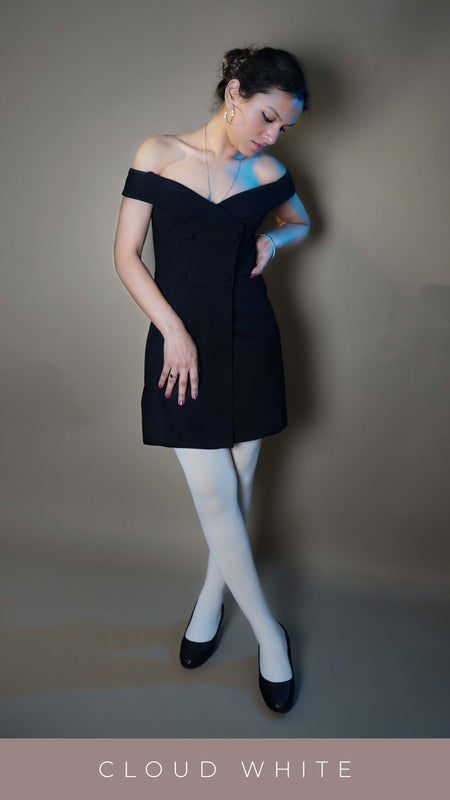 A stylish model wearing semi opaque girl's white stockings, posing with her hand on her waist and other on her thigh as she looks downward at her feet, highlighting the smooth durable material-Muselot