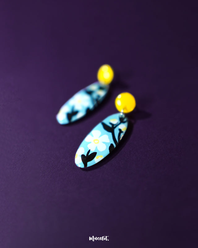 A pair of Shaamgul drop earrings displayed flat, showcasing the handcrafted floral elements and beadwork in a graceful, symmetrical layout — Muselot.