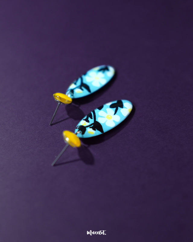 A pair of Shaamgul drop earrings laid flat, highlighting the handcrafted floral details and the graceful drop structure, perfect for a statement ethnic look — Muselot.