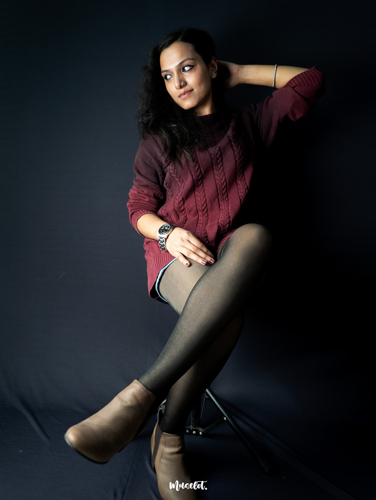 A model wearing a sheer fur stockings sitting on a chair crossing her legs, showcasing the comfortablity of the stockings- Muselot