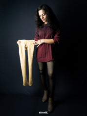 A model is holding a sheer fleece stockings, showcasing the stretchability of the stockings- Muselot