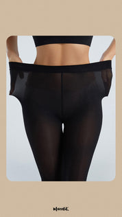 A model, wearing Silken Touch Premium Black Sheer Pantyhose, is stretching the waistband to showcase its flexible, comfortable fit. The sheer black fabric highlights a smooth, elegant look, perfect for adding sophistication and style to any outfit. -Muselot