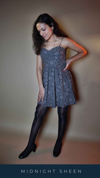 A woman posing with her hand on her waist and her thigh as she slightly bends forward, smiling, wearing black sheer pantyhose, showcasing the comfortable modern look-Muselot