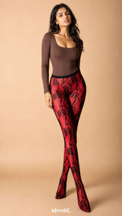 The model wears black rose lace stockings over red opaque stockings, highlighting the dramatic floral pattern, rich red base and complete waist-to-toe layered look – Muselot.