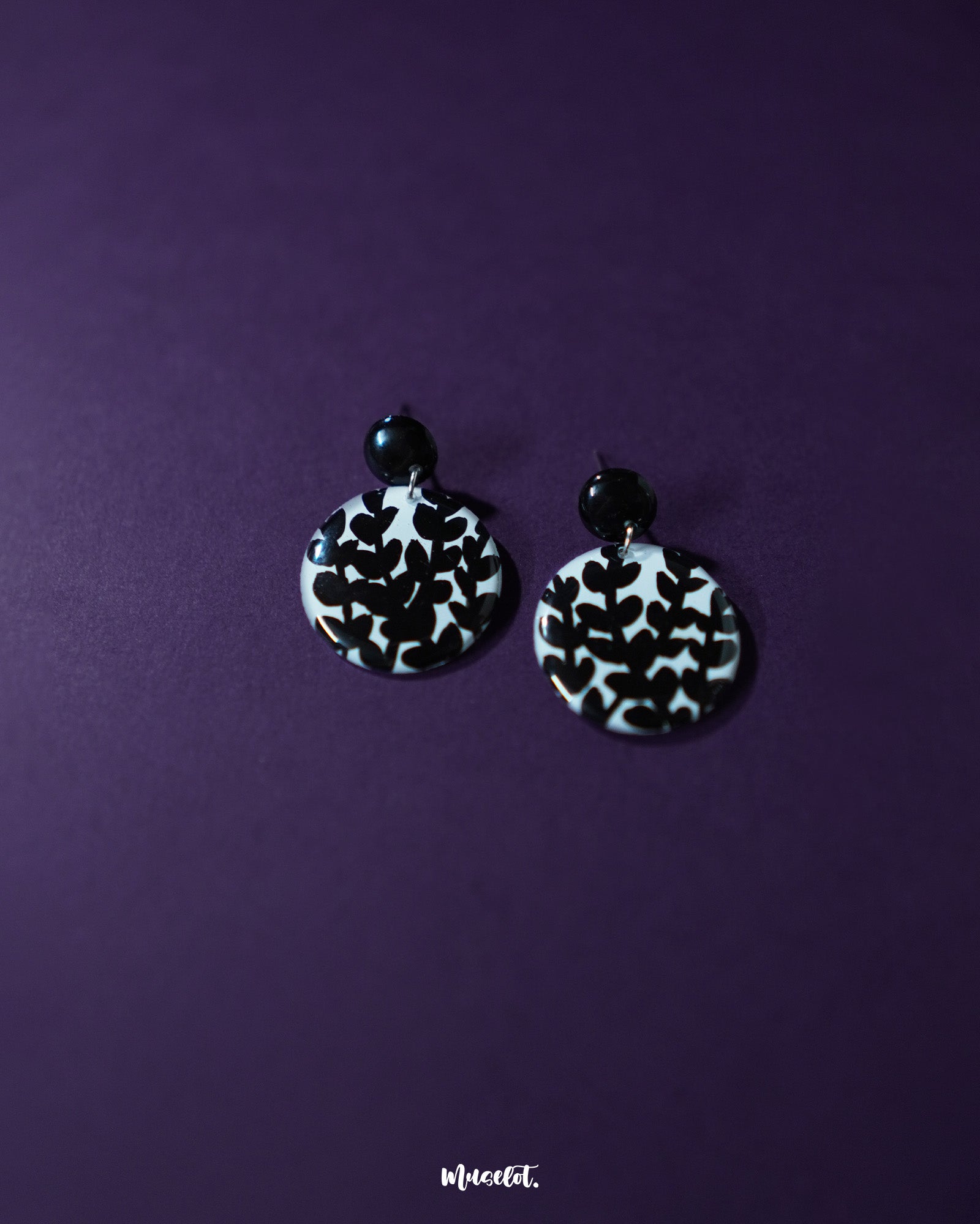 Siyahgul black floral stud earrings, elegantly set against a deep purple background, with intricate floral detailing and a sleek black finish that captures a perfect balance of drama and sophistication — Muselot.