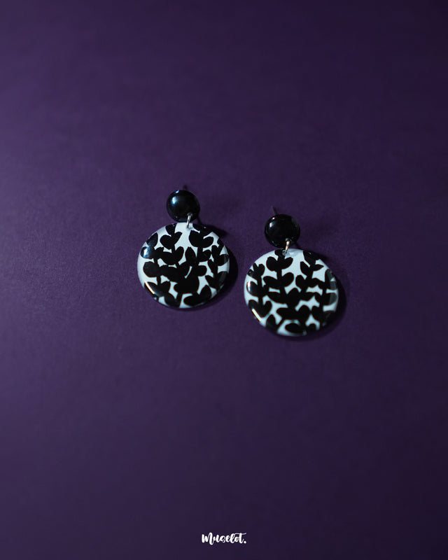 Siyahgul black floral stud earrings, elegantly set against a deep purple background, with intricate floral detailing and a sleek black finish that captures a perfect balance of drama and sophistication — Muselot.