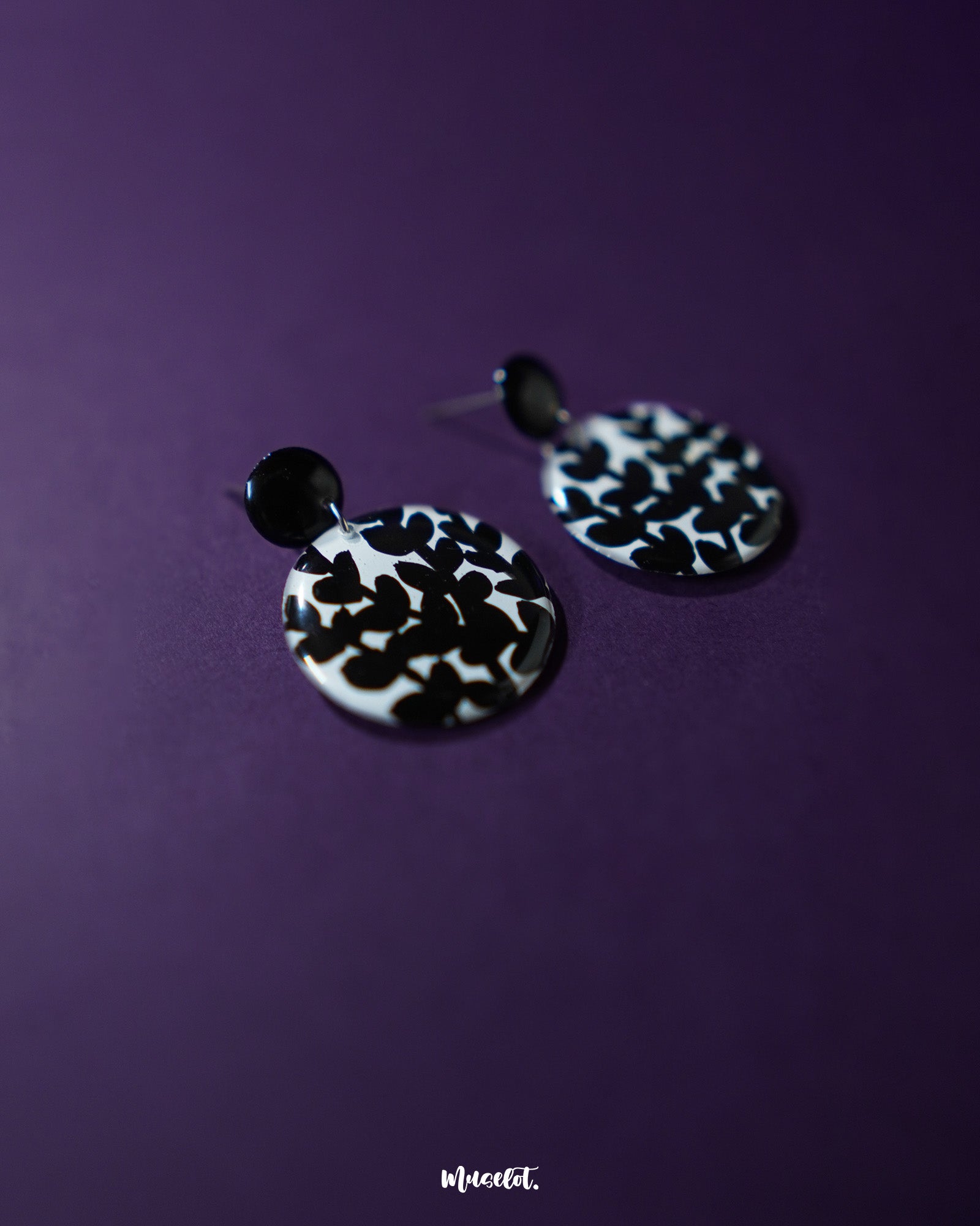 Siyahgul black floral stud earrings, showcased against a dark purple backdrop, with intricate floral patterns and a bold black finish that exude modern sophistication and timeless elegance — Muselot.