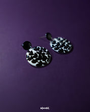 Siyahgul black floral stud earrings, showcased against a dark purple backdrop, with intricate floral patterns and a bold black finish that exude modern sophistication and timeless elegance — Muselot.